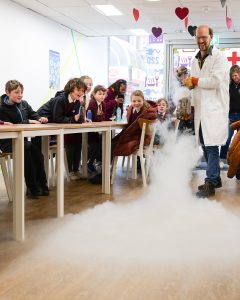 School children watch as Gunnar sprays the floor with a cloud-like gas