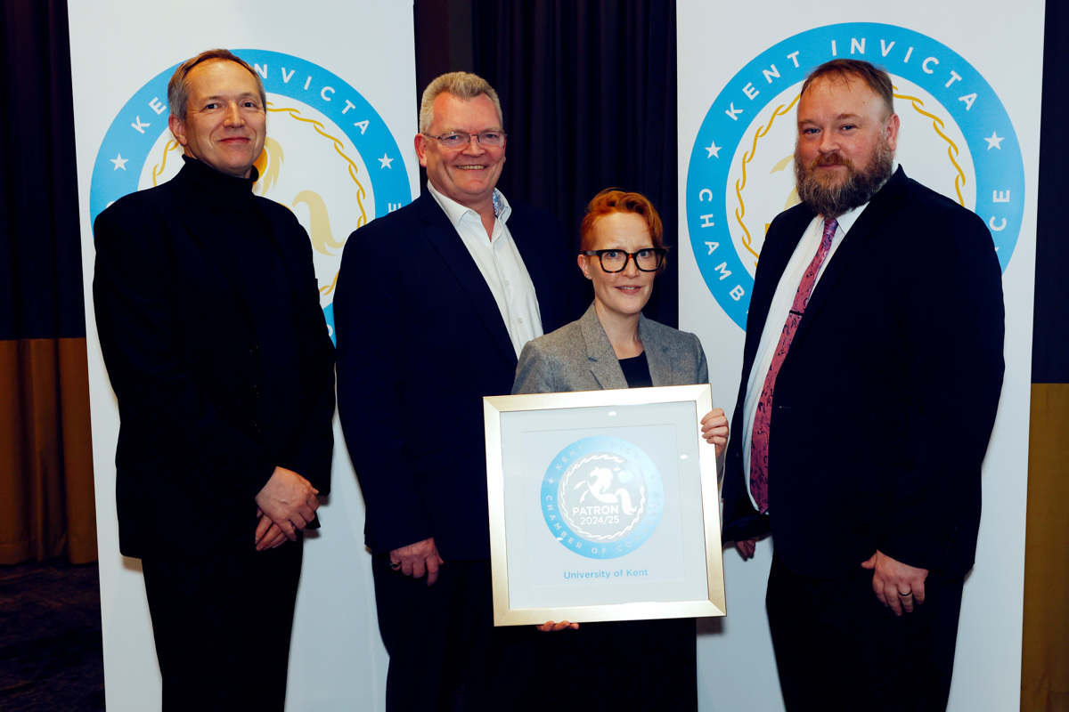 Kent and Chamber representatives pose with Patron certificate in front of branded banners