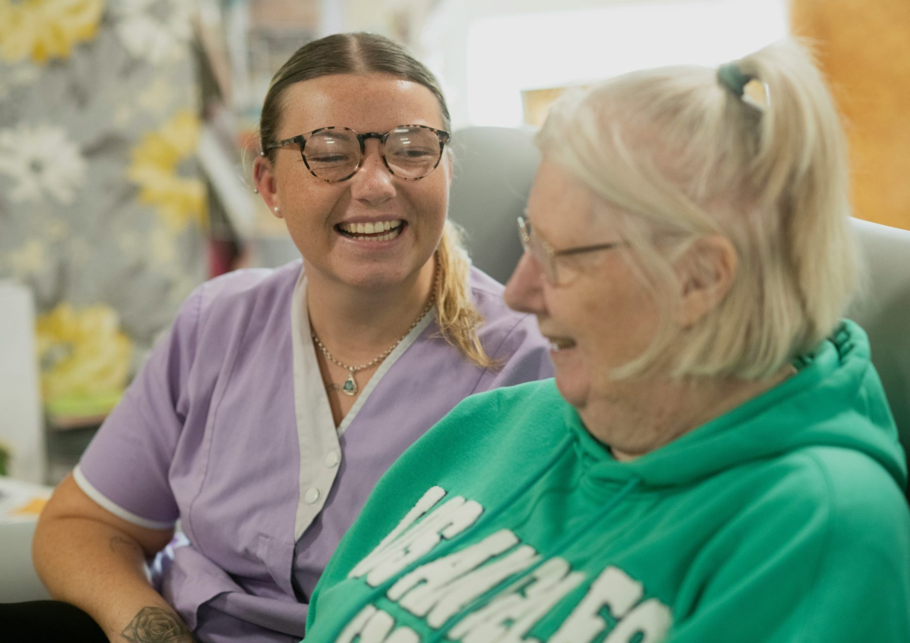 A social care worker laughs alongside a resident in a care home setting