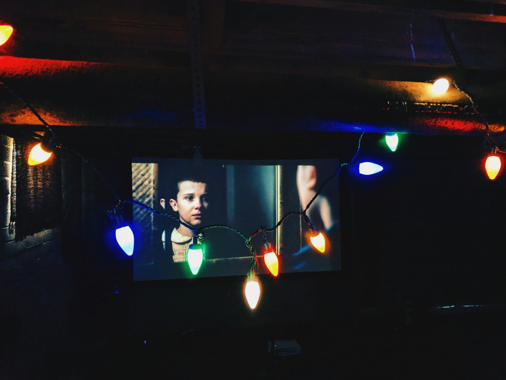 Stranger Things showing on a TV screen with colourful string lights in the foreground