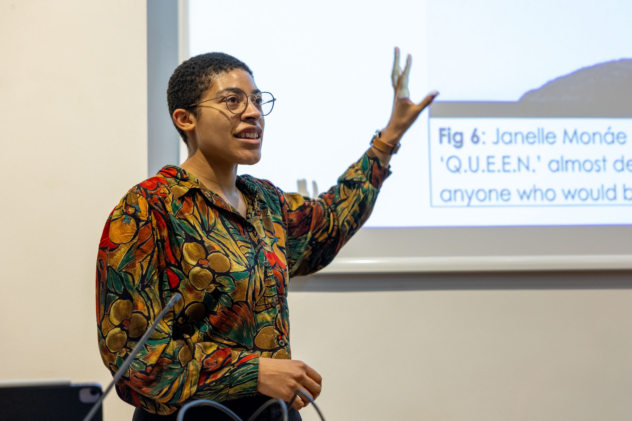 A speaker at the event talks animatedly in front of a screen